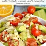 Bowl of salad and a lemon with text overlay: Hearts of Palm Salad with Avocado, Tomato, and Cucumber.