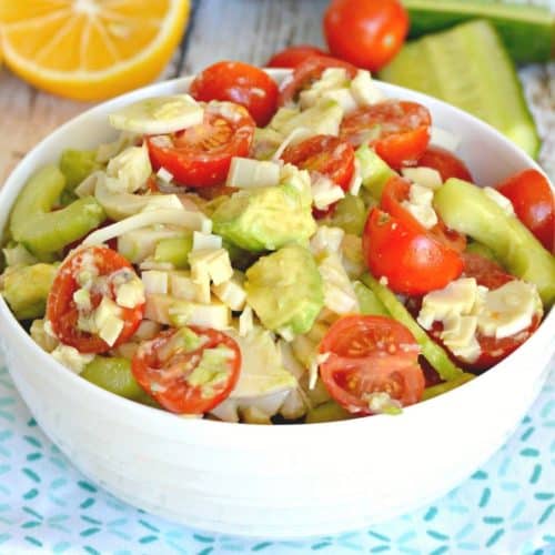 Bowl of avocado and hearts of palm salad with lemon in background