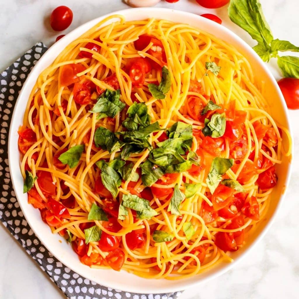 Serving bowl of pasta topped with fresh tomato basil sauce