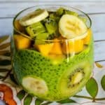 Green chia pudding with kiwi, mango, and banana in a glass