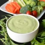 Bowl of Green Goddess Dressing with a platter of raw vegetables in the background