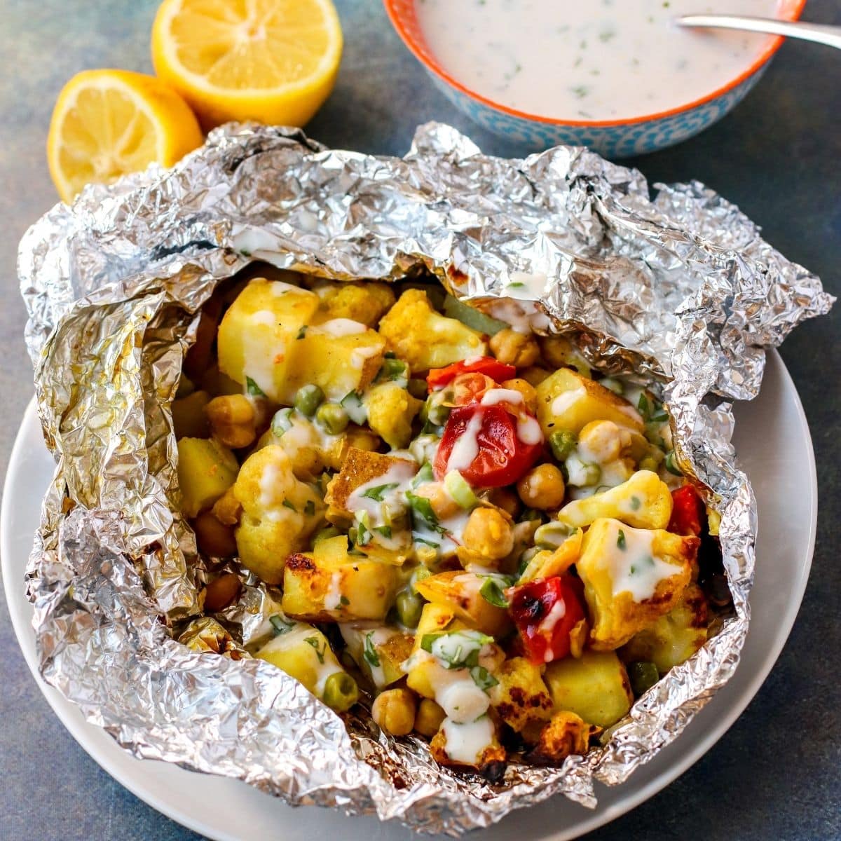 Foil grill packet open on a plate and drizzled with sauce