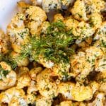 Roasted cauliflower garnished with fresh dill, with text overlay: Dijon Mustard Roasted Cauliflower.