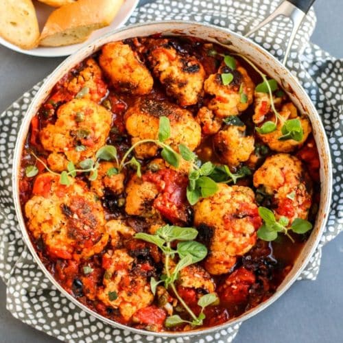 Cauliflower in a skillet topped with sauce.