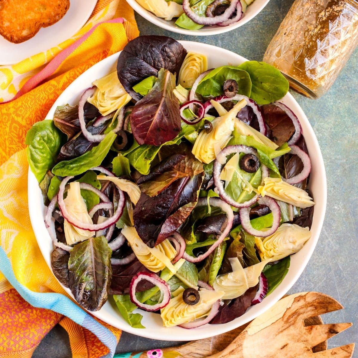 Overhead of serving bowl of salad with jar of dressing next to it