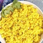 Bowl of yellow rice with pine nuts and cilantro, with text overlay: Mediterranean Yellow Rice (Easy 30-Minute Recipe).