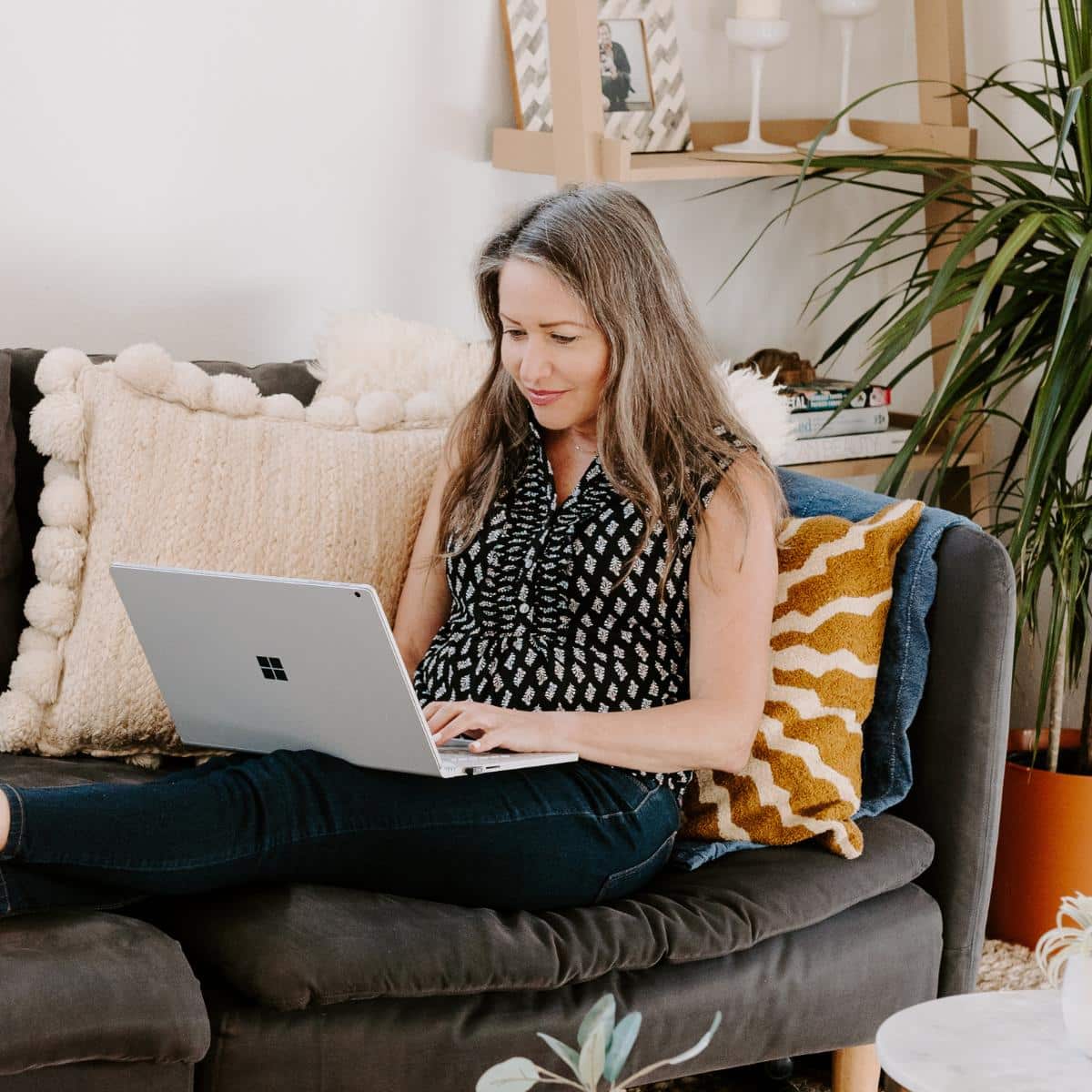Amy sitting on a couch with her laptop computer.