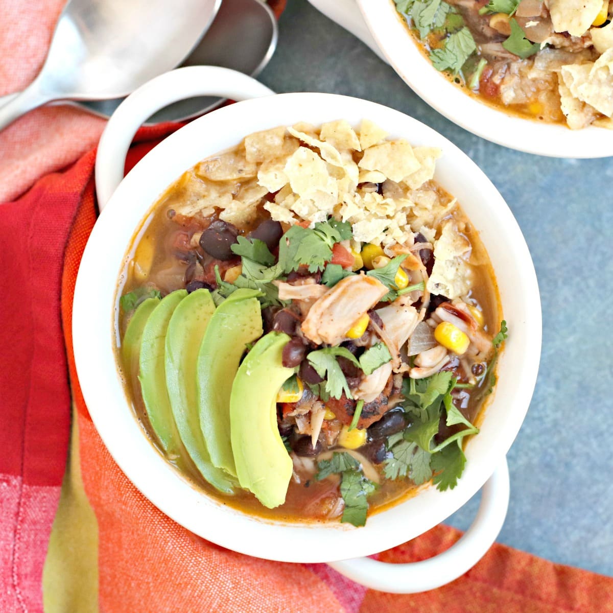 Bowl of Vegan Taco Soup garnished with avocado slices, fresh cilantro, and crushed tortilla chips.