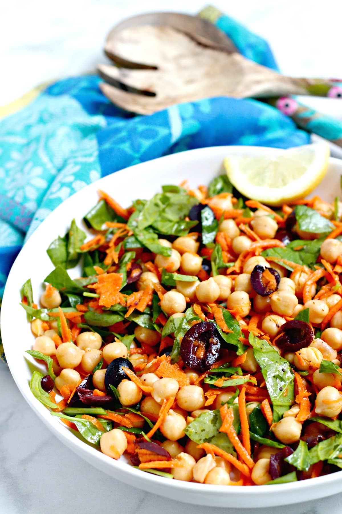 Close up of Chickpea Spinach Salad in a serving bowl garnished with a lemon wedge