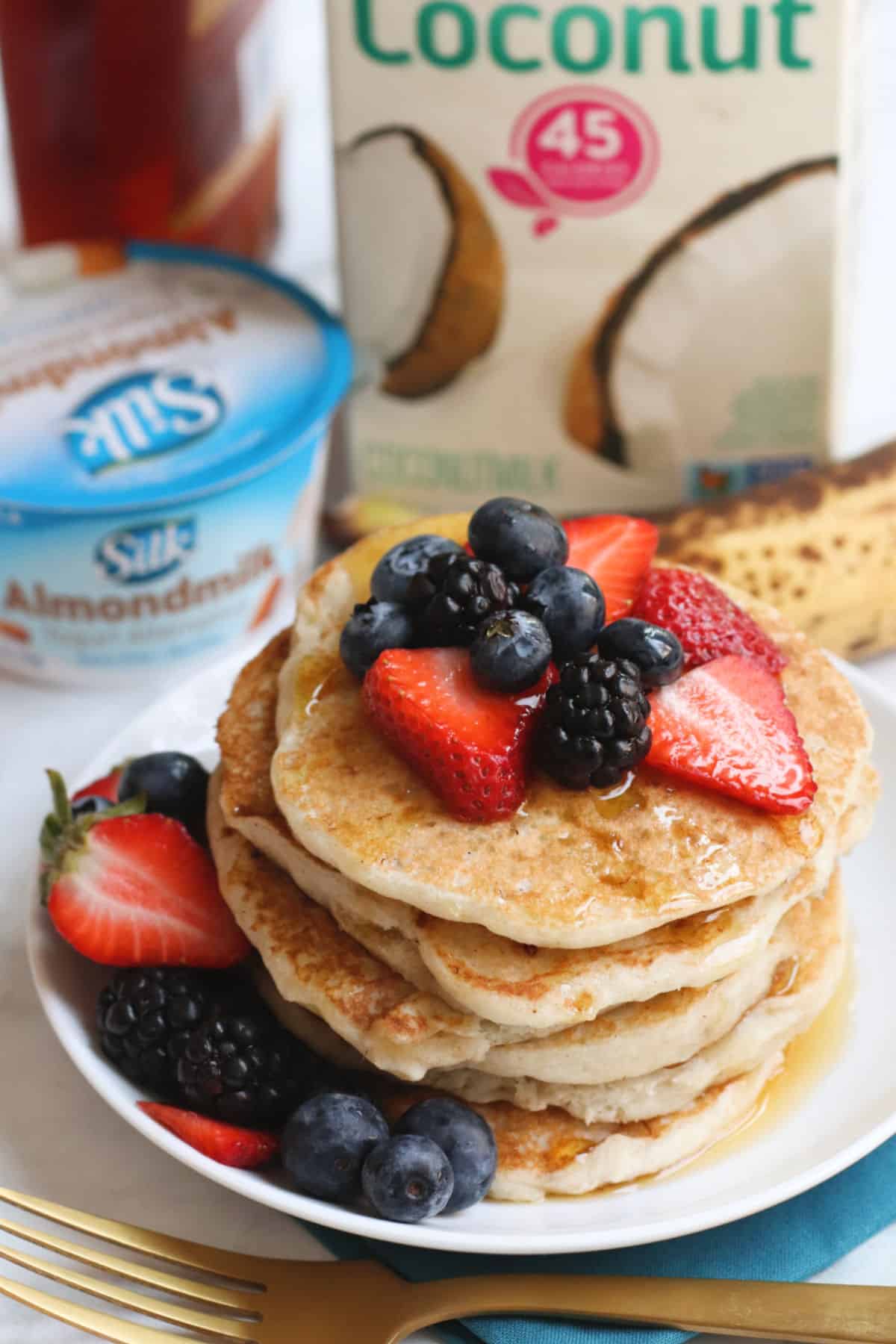 Plate of pancakes with carton of coconut milk and container of almond milk yogurt in the background