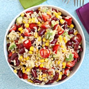 Overhead of bowl of brown rice salad with kidney beans, avocado, corn, and tomatoes