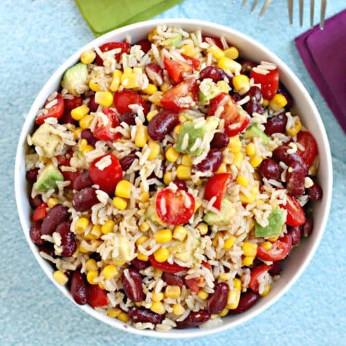 Overhead of bowl of brown rice salad with kidney beans, avocado, corn, and tomatoes.