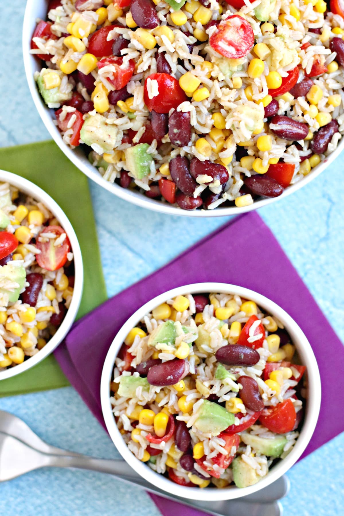 Overhead of bowls of salad with purple and green napkins