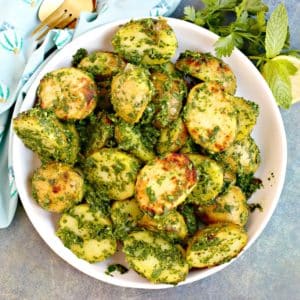 Bowl of grilled potatoes tossed in fresh herb sauce.