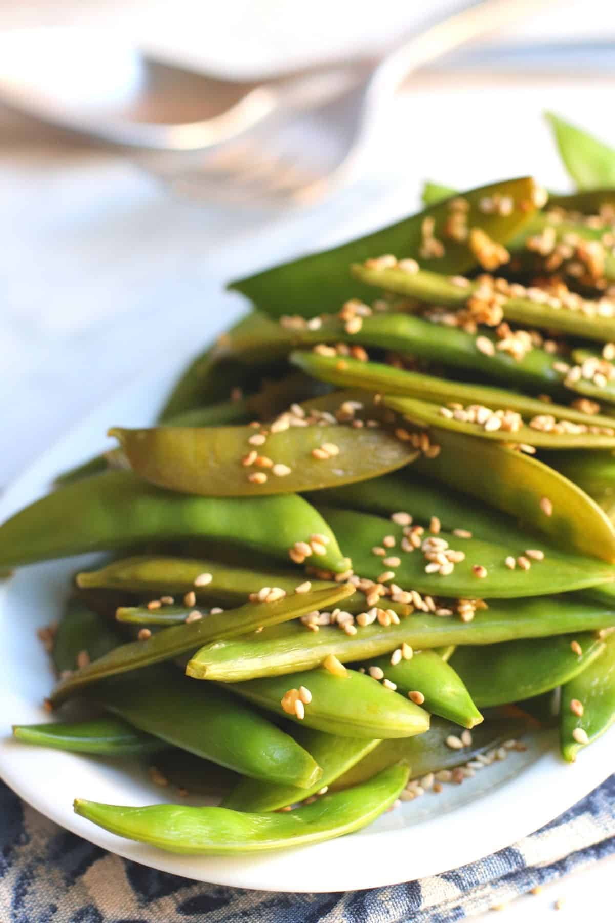 Platter of stir fried snap peas garnished with toasted sesame seeds