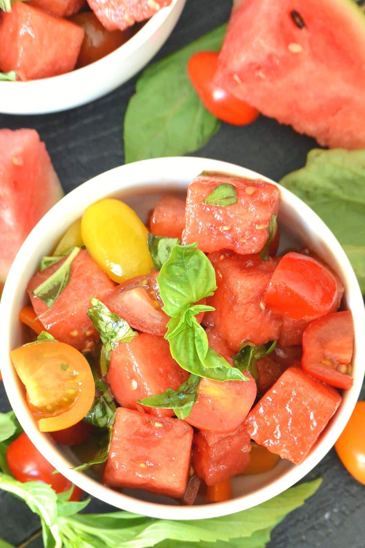 Overhead of white bowl filled with salad and garnished with sprig of basil