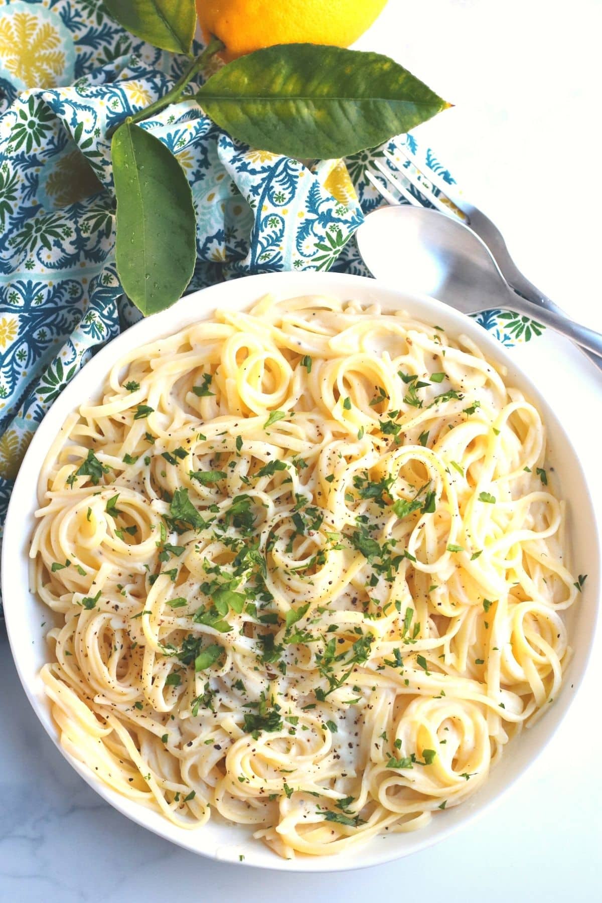 Overhead of bowl of fettucine pasta topped with a creamy vegan sauce and chopped parsley