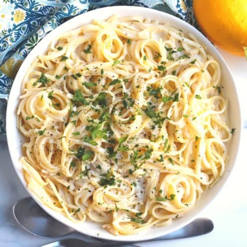 Overhead of bowl of pasta topped with cauliflower alfredo sauce and fresh parsley