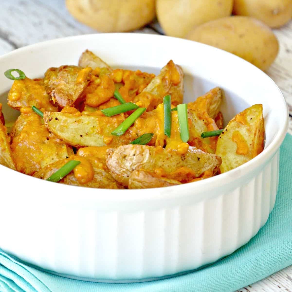 Serving bowl of potato wedges topped with cheesy sauce