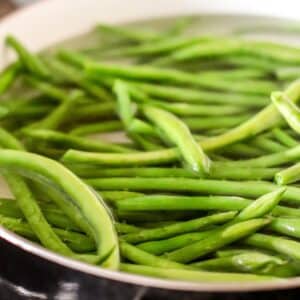 Fresh green beans blanching in a pot of simmering water.