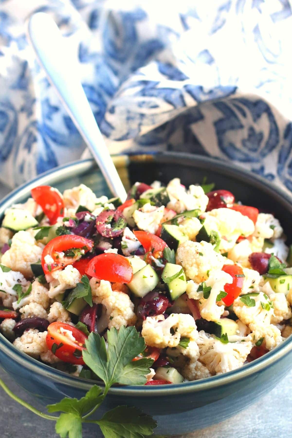 Cauliflower salad in a bowl with serving spoon in it.