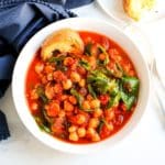 Bowl of stew with a piece of bread on the side.