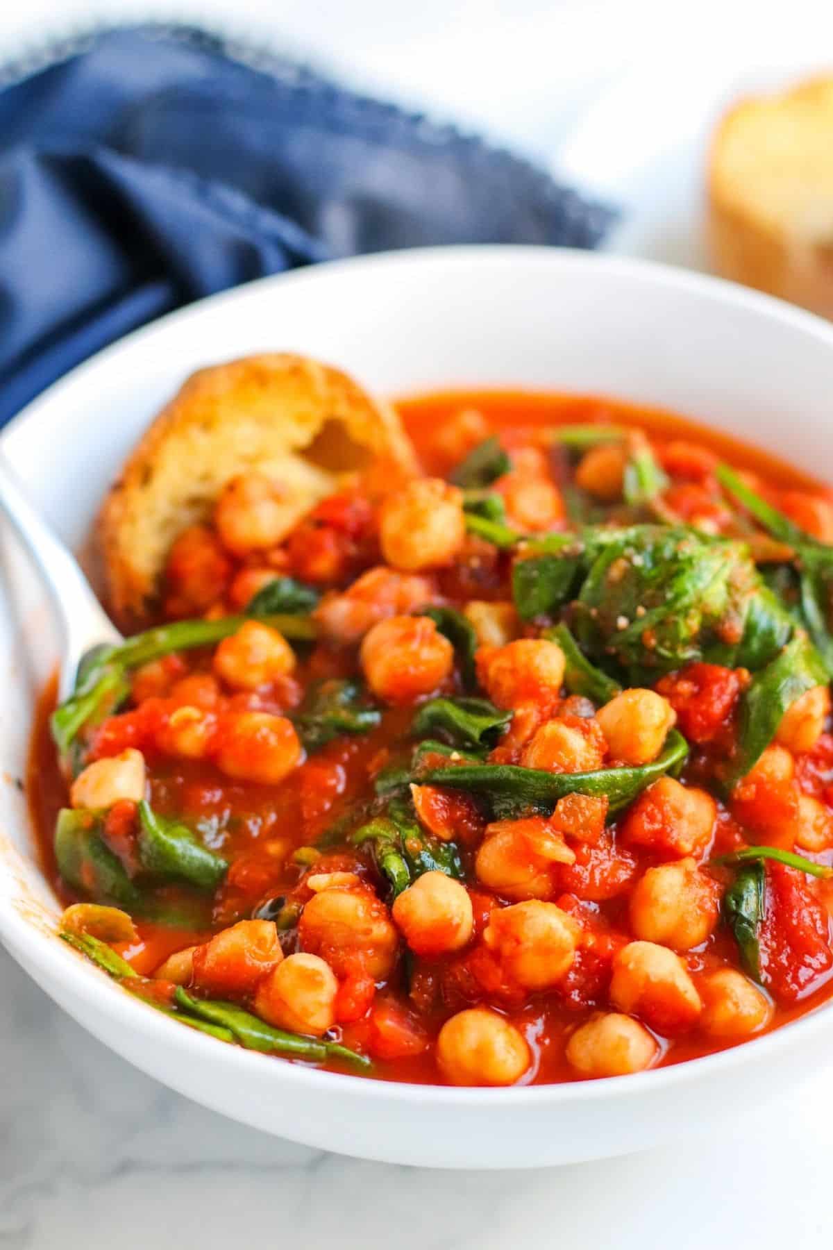 Closeup of bowl of chickpea stew with a spoon in it.