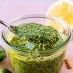 Bowl of green sauce with a spoon in it and text overlay Vegan Pesto.