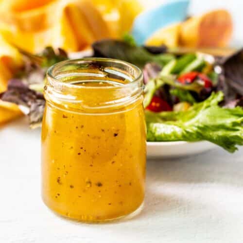 Dressing in a jar next to a salad.