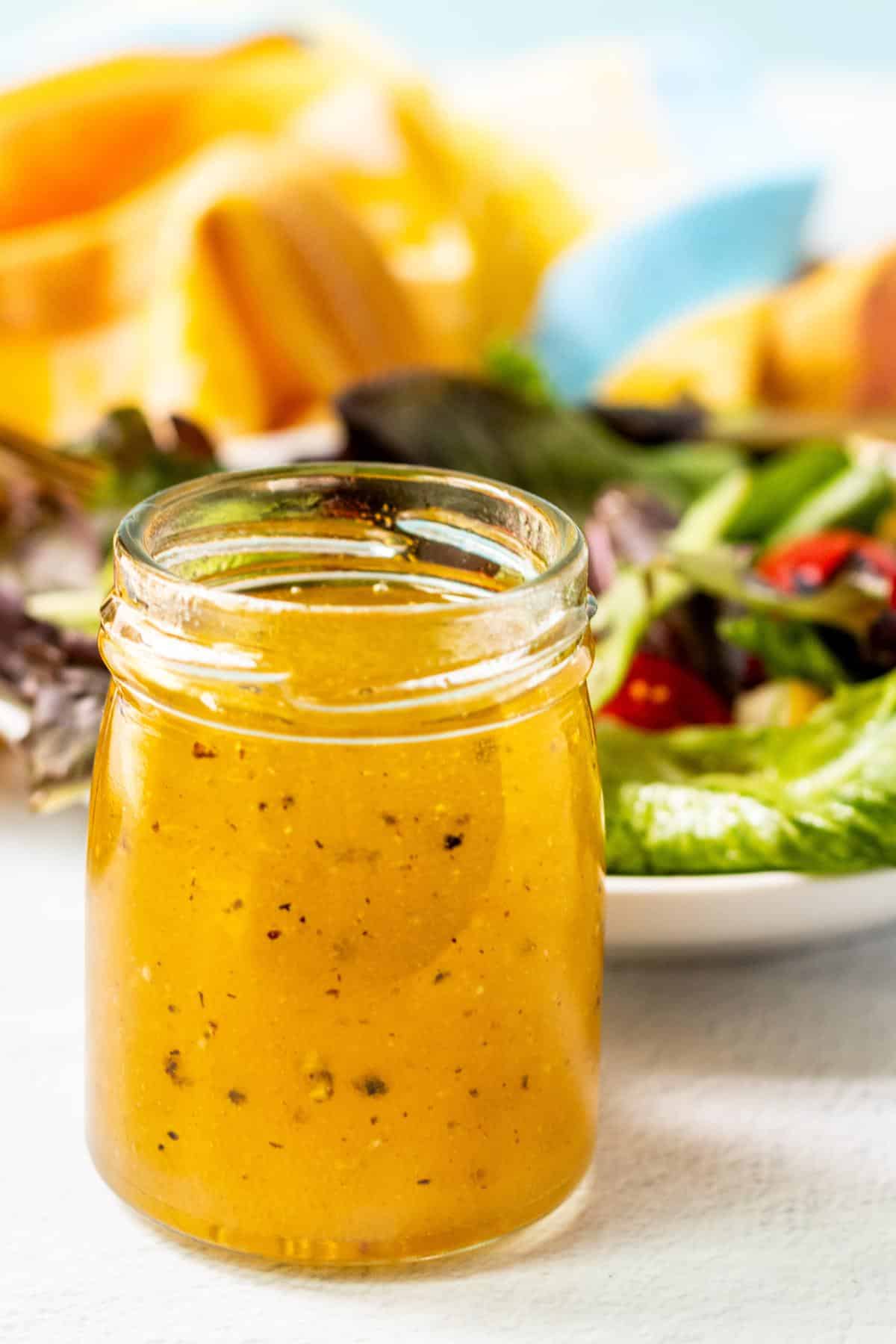 Jar of white balsamic vinaigrette next to a salad.