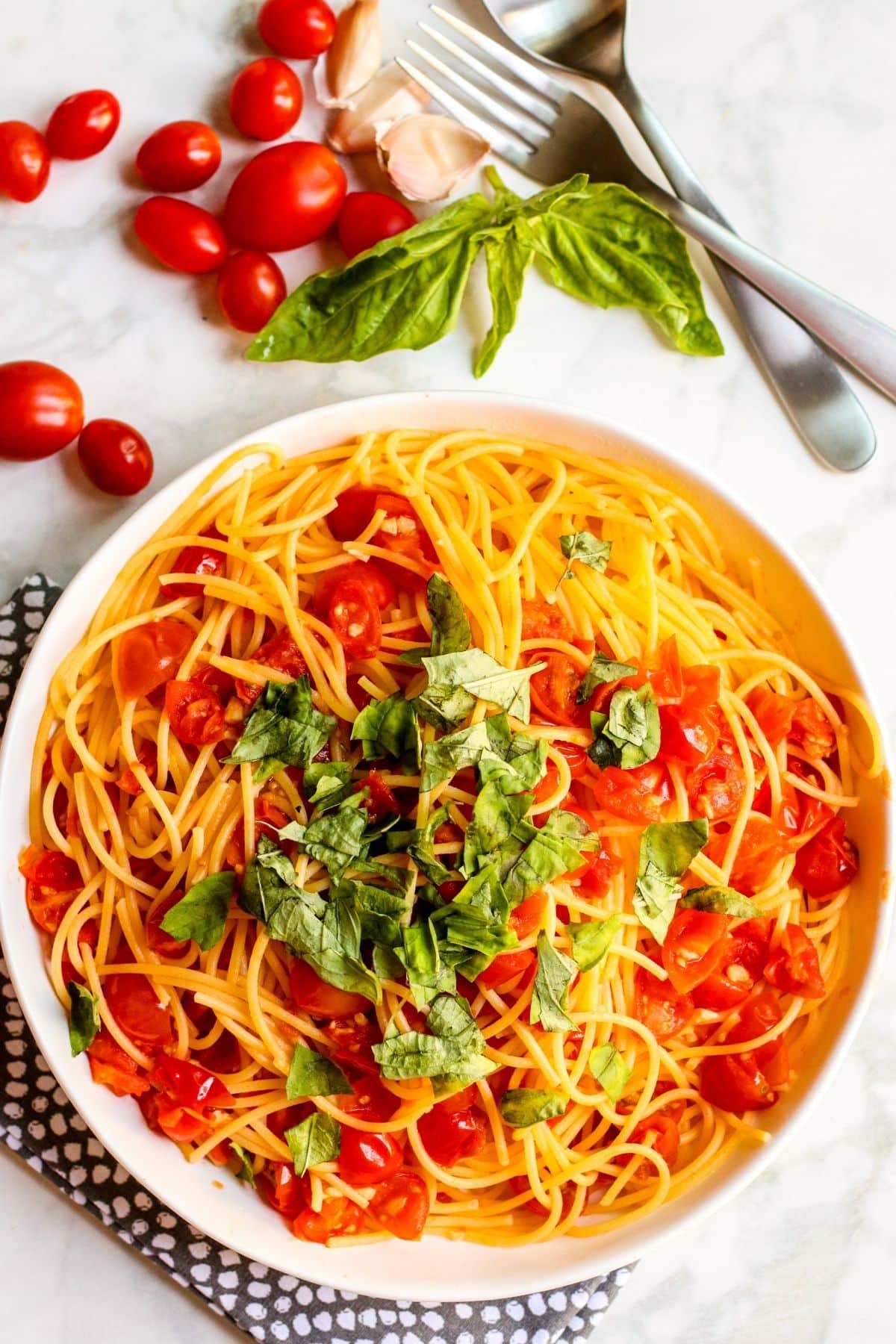 Overhead of a bowl of Angel Hair Pomodoro topped with freshly torn basil leaves