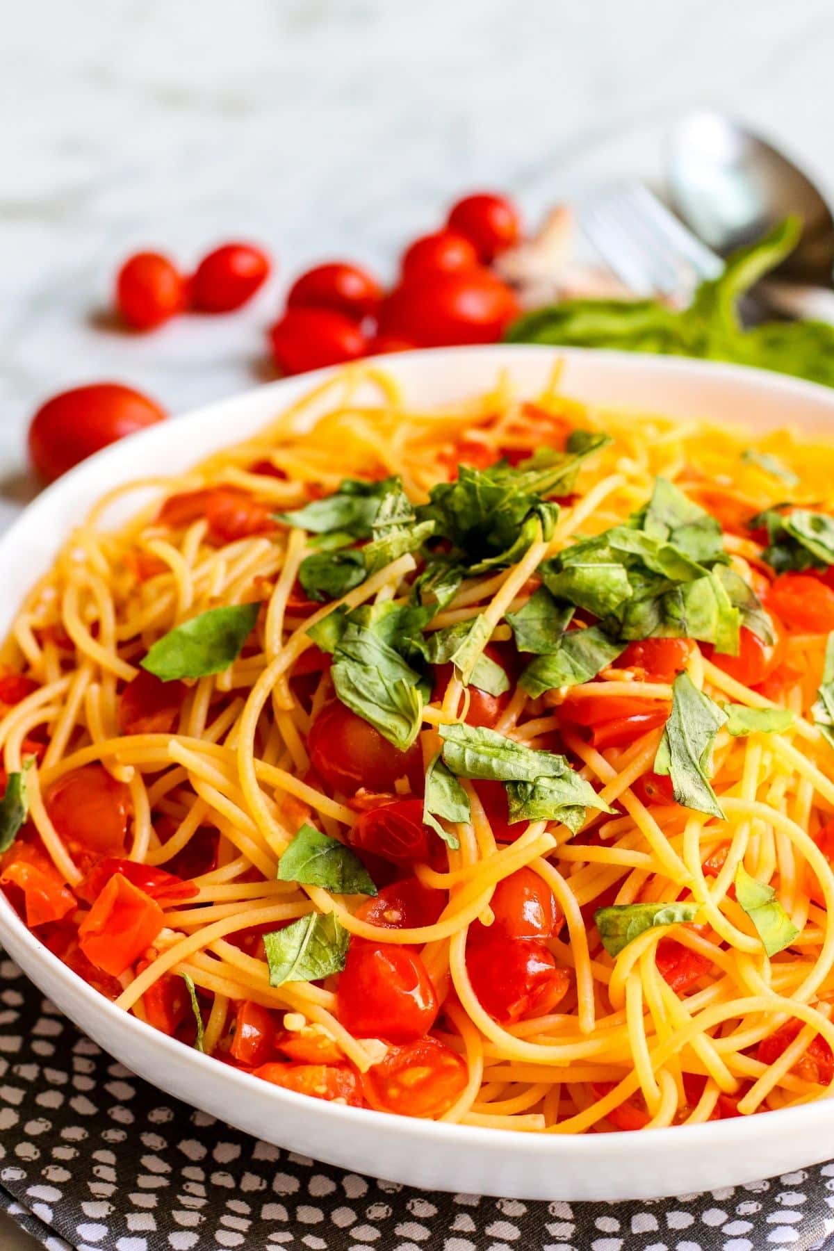 Close up of serving bowl of pasta pomodoro topped with fresh basil