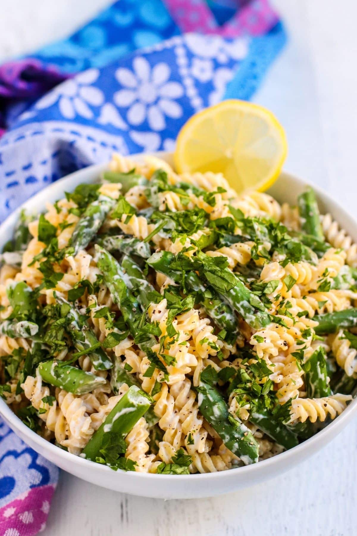 Close up of bowl of pasta with asparagus topped with chopped parsley