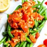 Platter of green beans topped with garlicky tomatoes and pine nuts.