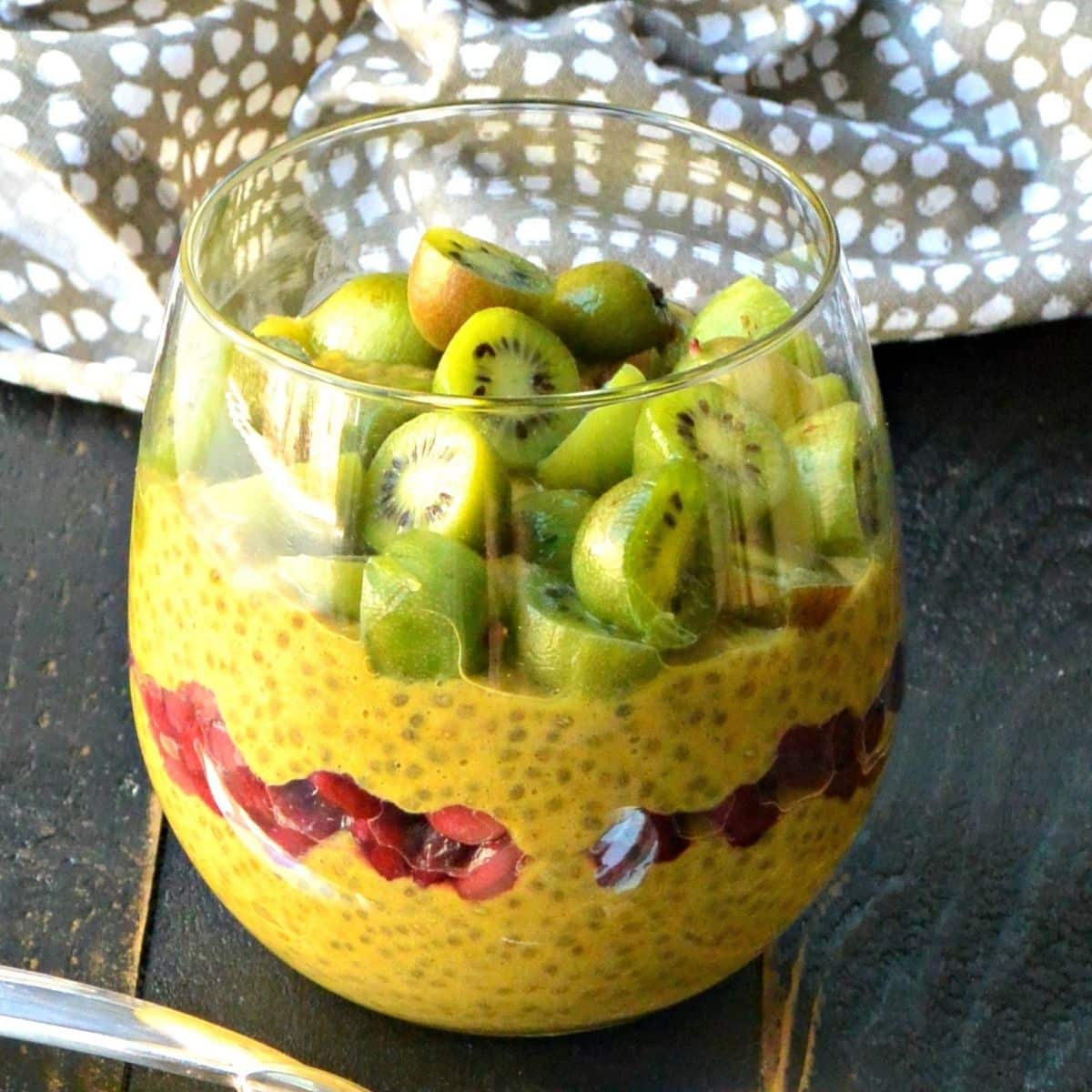 Pumpkin pie chia pudding in a glass layered with pomegranate seeds and topped with kiwi berries