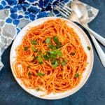 Bowl of spaghetti and tomato sauce garnished with fresh herbs