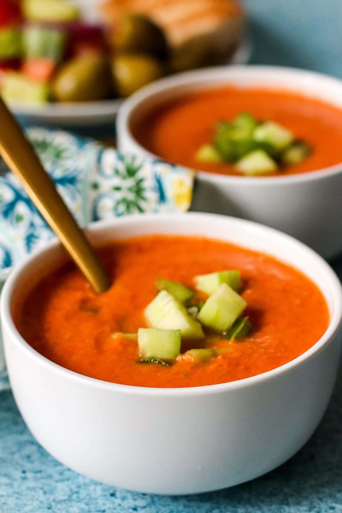 Bowls of gazpacho garnished with cubes of cucumber and green bell pepper