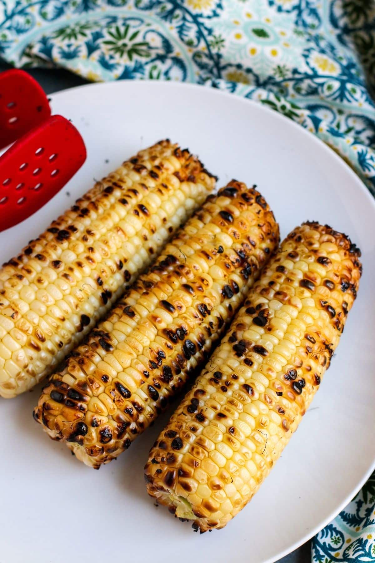 3 ears of grilled corn on a white plate