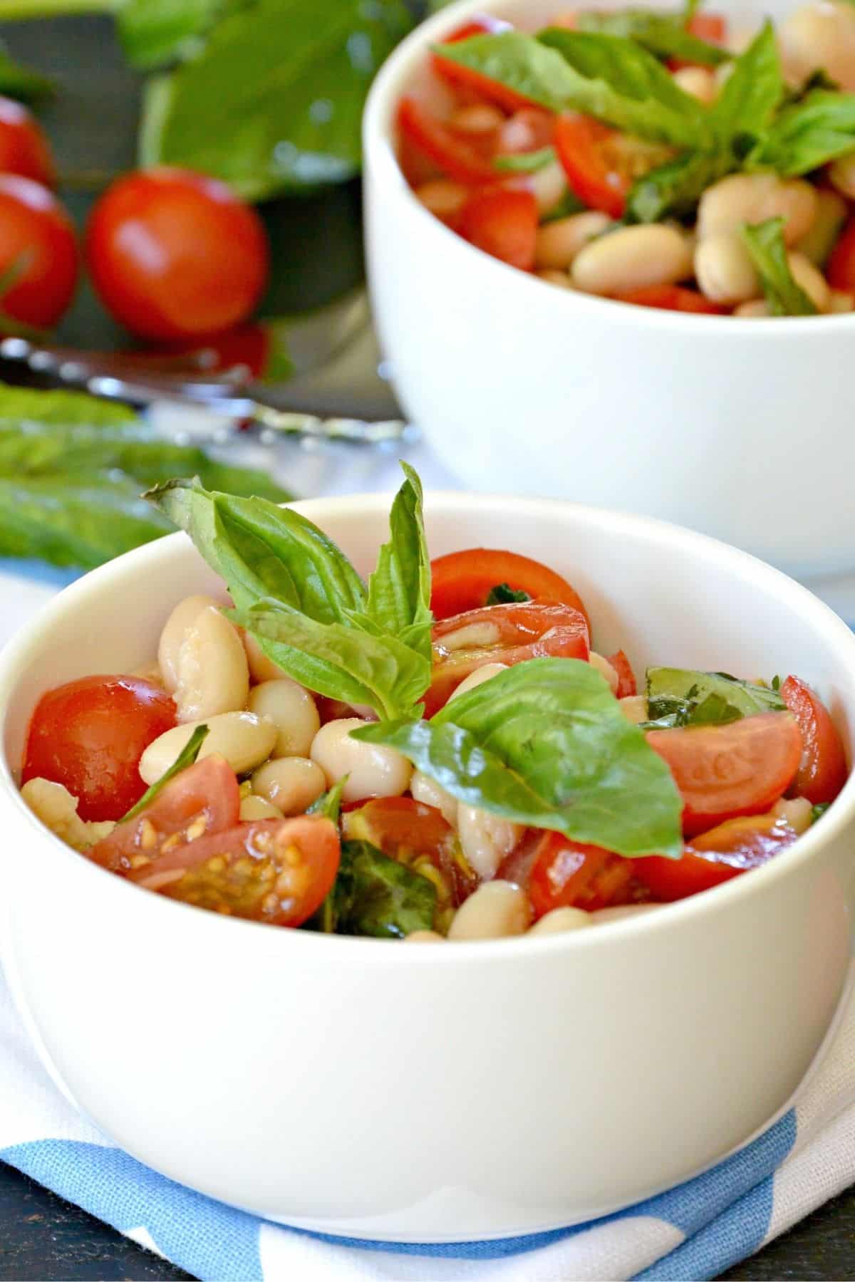 Bowls of Italian White Bean Salad topped with sprigs of fresh basil