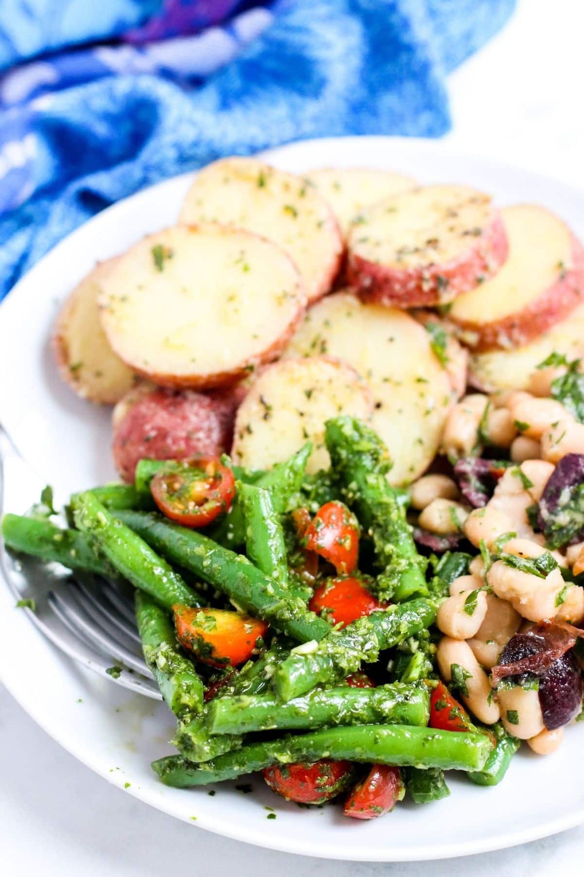 Plate of potato salad, cannellini bean salad, and Mediterranean green bean salad
