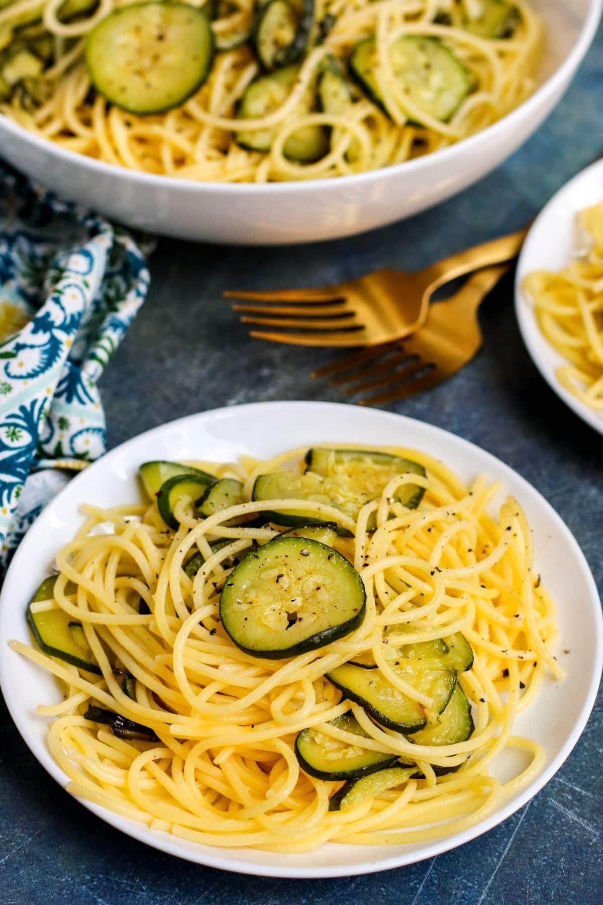 Serving of pasta on a plate with serving bowl in the background