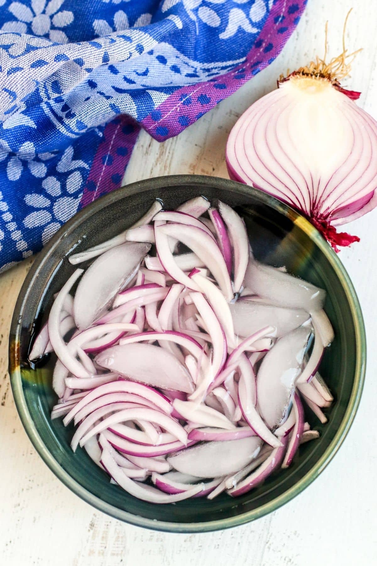 Onion slices soaking in a bowl of ice water.