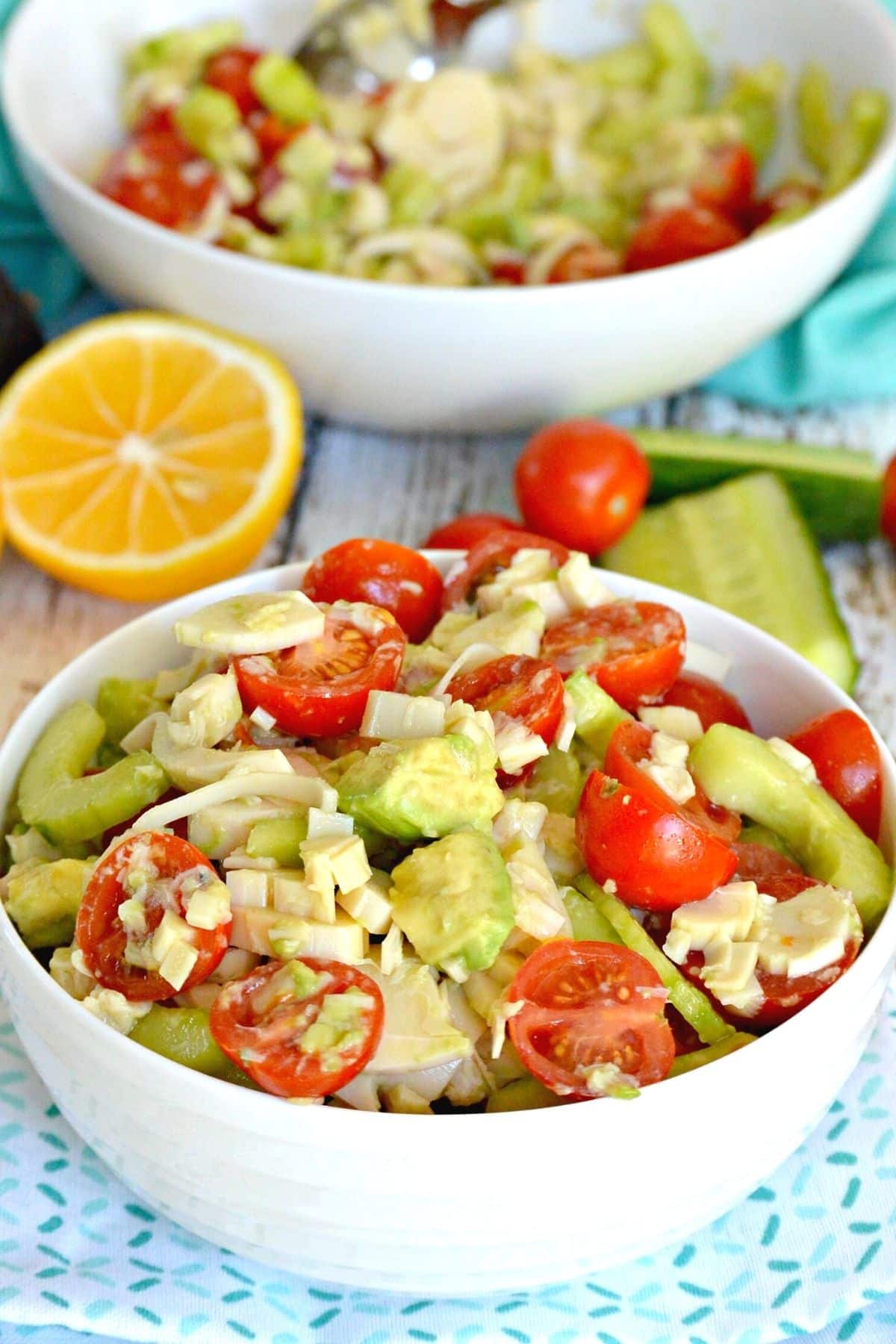 Bowl of salad with half a lemon in the background.