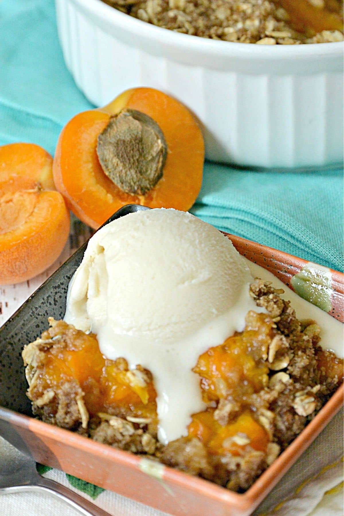 Serving of baked apricot dessert topped with scoop of vanilla ice cream