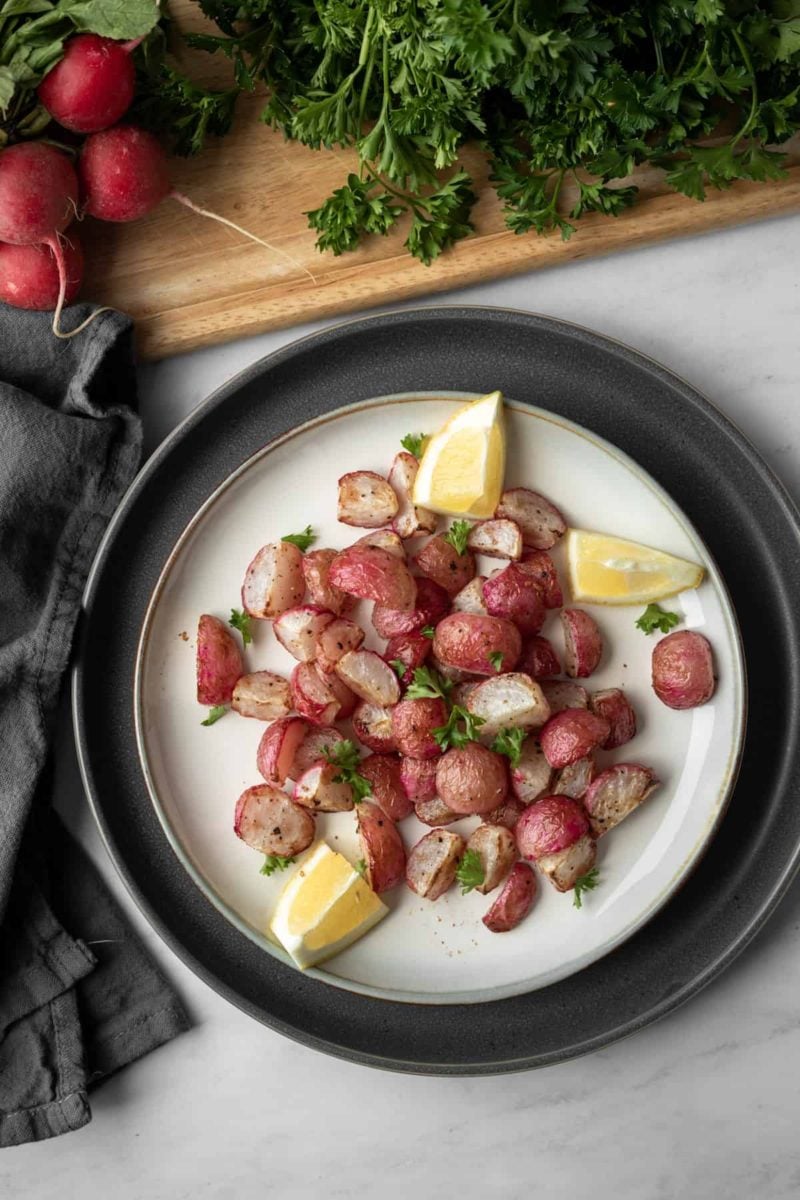 Roasted radishes and lemon wedges on a plate