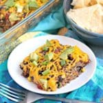 Slice of casserole on a plate topped with cubes of avocado and sliced green onions