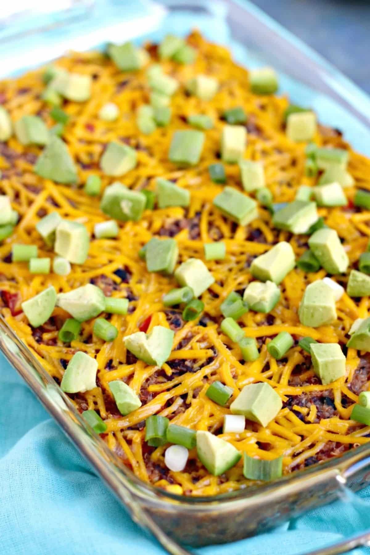 Baked casserole topped with sliced green onions and cubed avocado