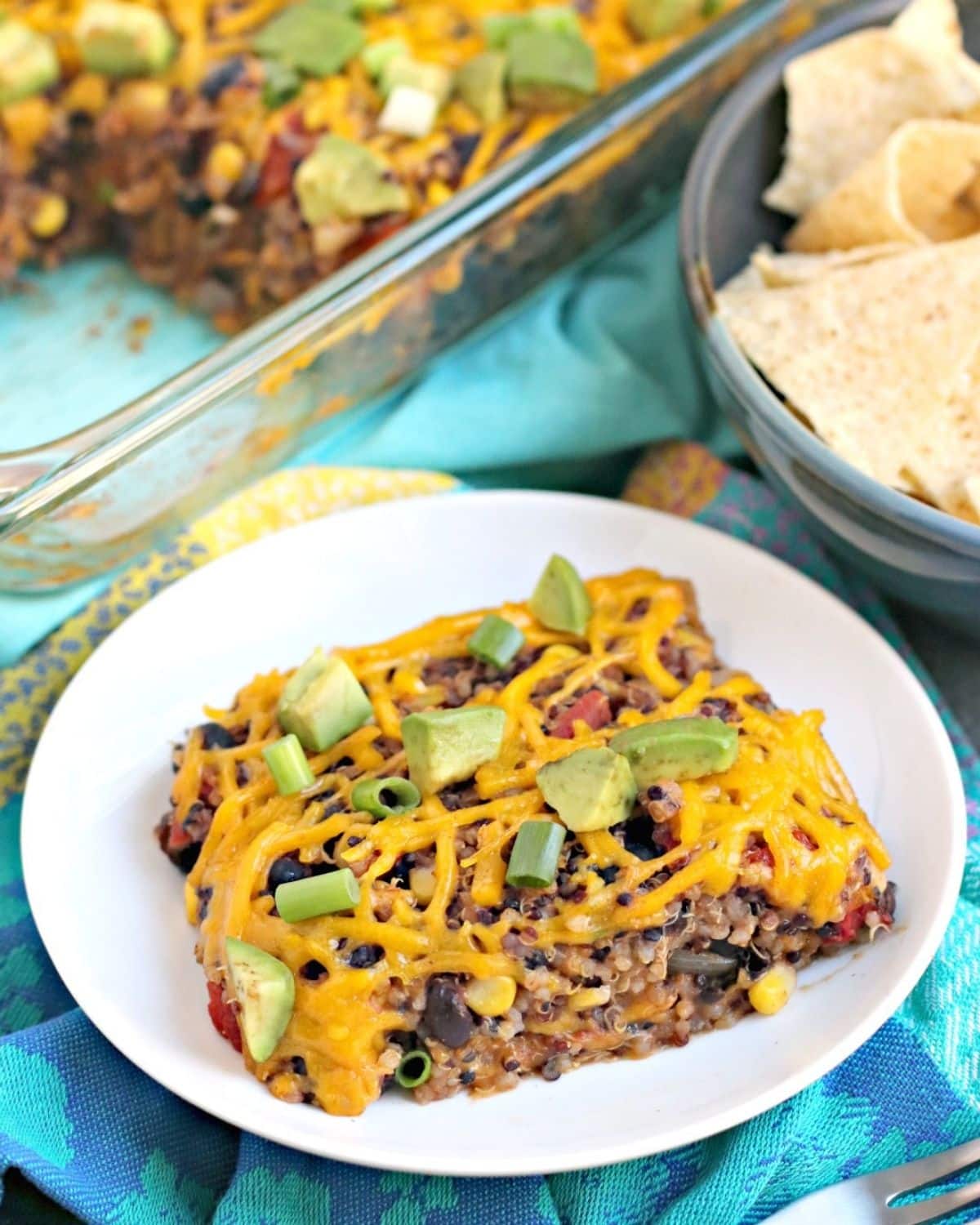 Portion of casserole on a plate topped with avocado and green onions