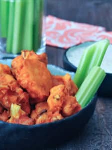 Buffalo cauliflower with celery sticks and bowl of Ranch dressing