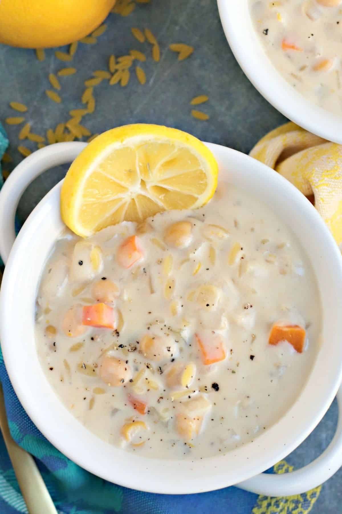 Overhead of bowl of chickpea orzo soup garnished with a slice of lemon